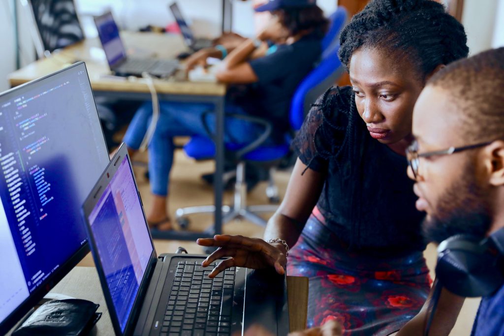 Two students looking at a laptop working on online web development