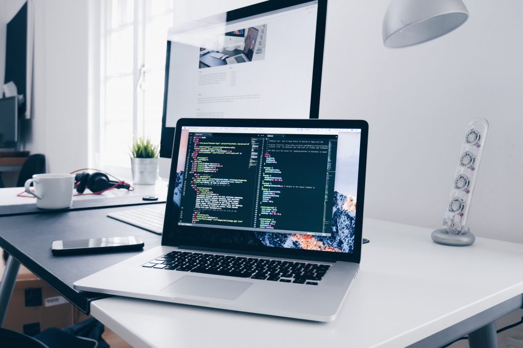 Laptop on a desk showing web development code