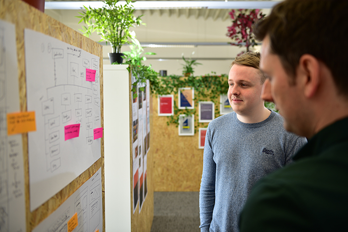 A picture of two team members looking at a cork board