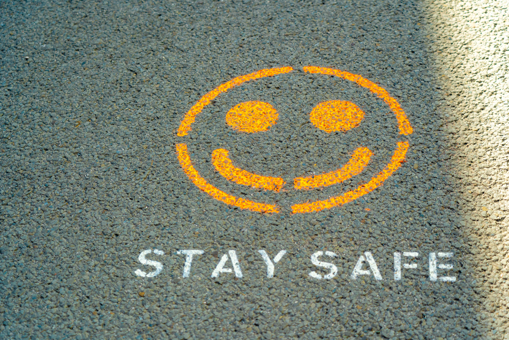 A smile spray painted onto the floor with stay safe written underneath